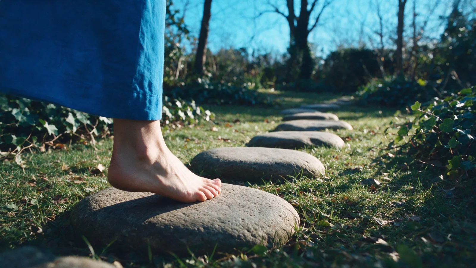 Un piede scalzo si posa sulla prima pietra di un sentiero in giardino