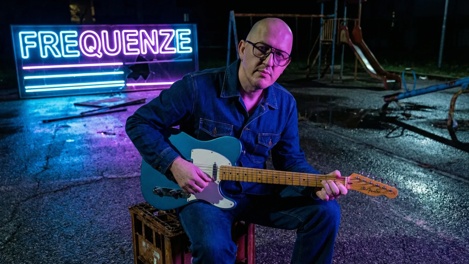 Marco Maso suona la Telecaster davanti all'insegna al neon di Frequenze
