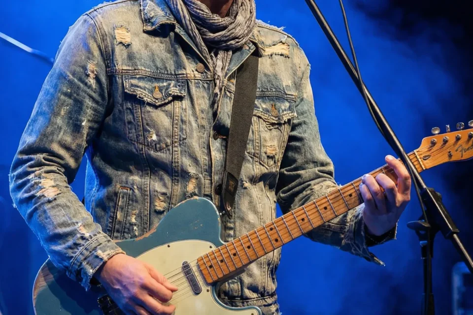 Marco Maso canta e suona dal vivo su un palco illuminato di blu