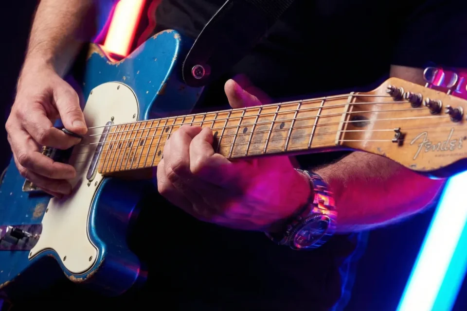 Primo piano delle corde di una Telecaster tra luci al neon