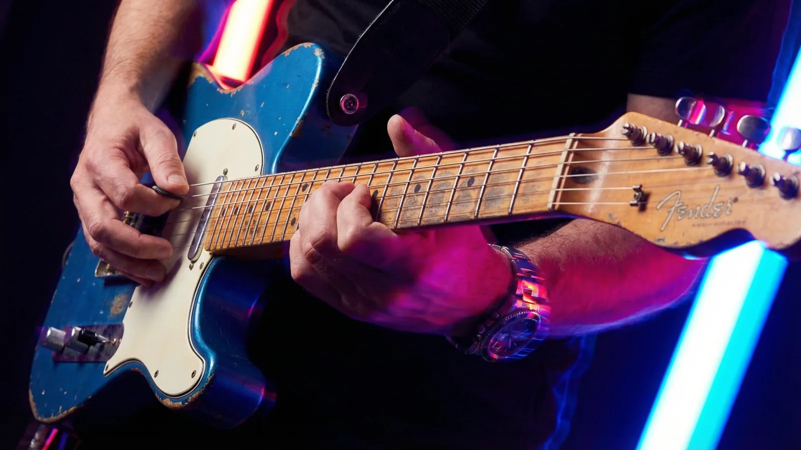 Primo piano delle corde di una Telecaster tra luci al neon